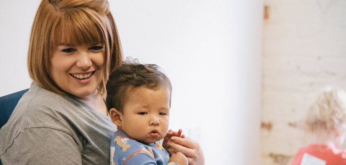 Smiling child care working holding a cute toddler