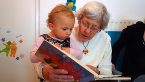 Stock photo of an older woman reading to a toddler.