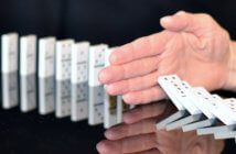Overcoming Apprehension about Change Hand trying to stop dominoes from falling