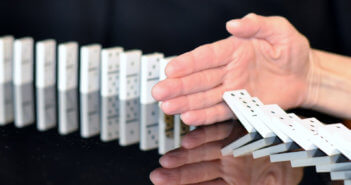 Hand trying to stop dominoes from falling