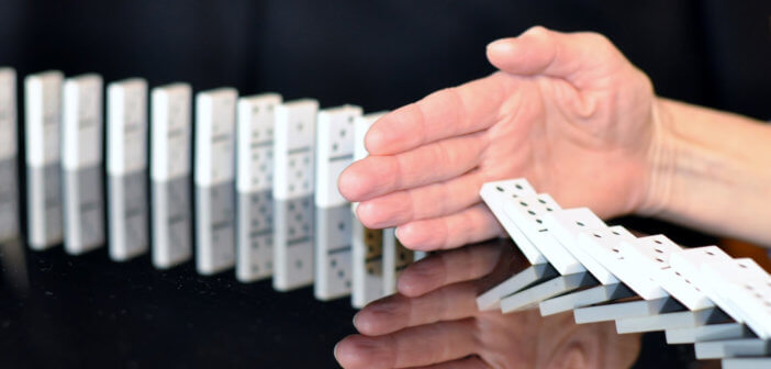 Hand trying to stop dominoes from falling