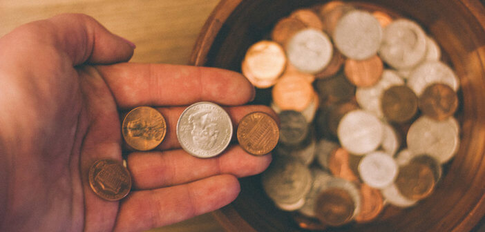 Close up of a hand dropping coins into a collection plate