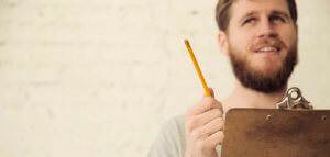 Person in thought while holding a clipboard and pencil