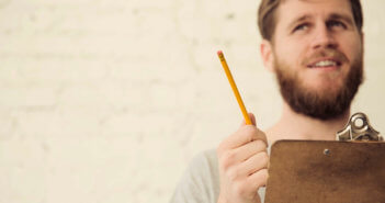 Person in thought while holding a clipboard and pencil