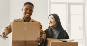 Smiling pastor and their spouse carrying moving boxes