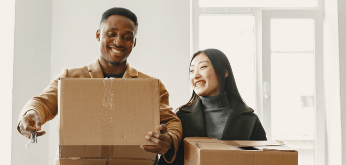 Smiling pastor and their spouse carrying moving boxes