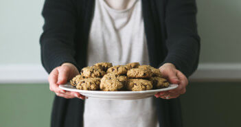 Person offering a plate of delicious cookies