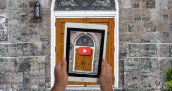 Person holding up a tablet with an image of a church door in front of said church door