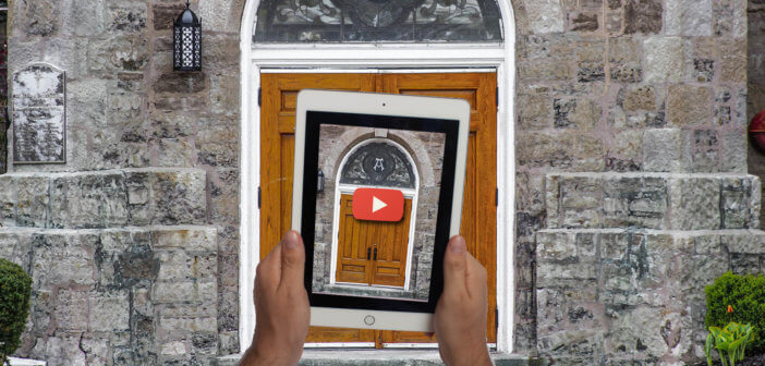 Person holding up a tablet with an image of a church door in front of said church door