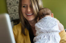 4 Ways A Weekday Childcare Webpage Can Connect Families with Your Church Parent typing on a computer while holding their infant