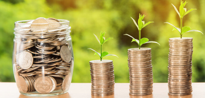 Jar of coins beside growing stacks of coins with seedlings sprouting from the top