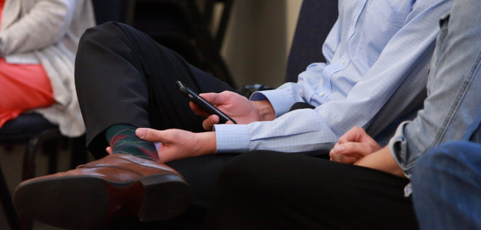 Person sitting in a worship service using their smartphone