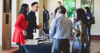 Friendly volunteers at a church information table chatting with other church members