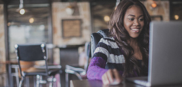 Smiling person using a laptop computer in a cafe