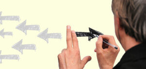 Person drawing arrows going forward in contrast to arrows going backward