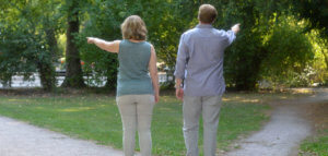 Two people pointing in different directions while standing on the crossroads of a path