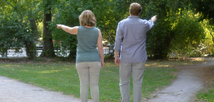 Two people pointing in different directions while standing on the crossroads of a path