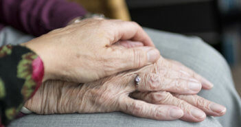 Person holding the hand of an older adult