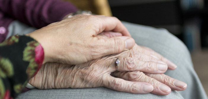 Person holding the hand of an older adult