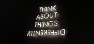 Neon sign reading THINK ABOUT THINGS DIFFERENTLY -- and differently is upside down