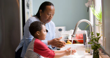 Adult teaching a child the proper way to wash their hands