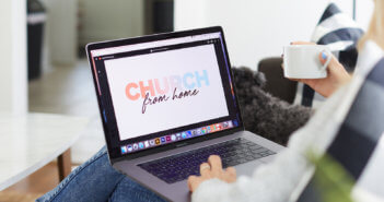 Person taking part in worship service on their computer while sitting on a couch in the living room