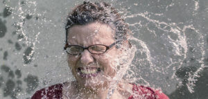 Grimacing person being pelted with large splashes of water