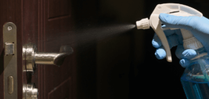 Spraying disinfectant on a doorknob
