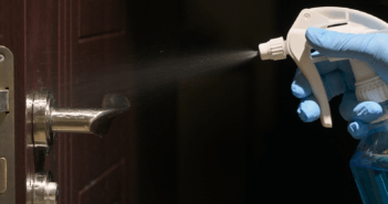 Spraying disinfectant on a doorknob