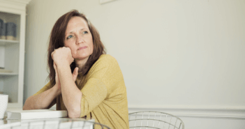 Middle-aged person sitting pensively at a table