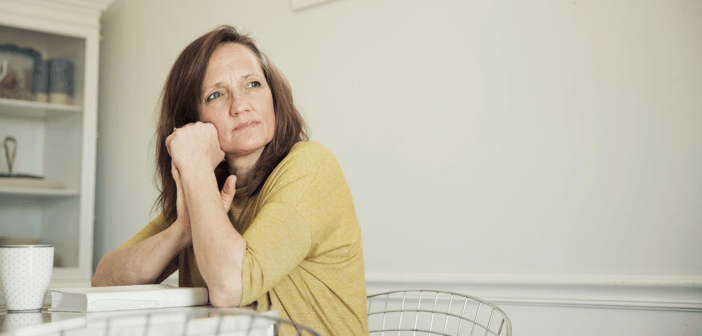 Middle-aged person sitting pensively at a table