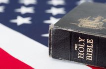 Leading between Faith and Patriotism Time-worn Bible resting upon an American flag