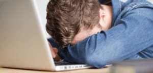Person with their head down on their computer keyboard
