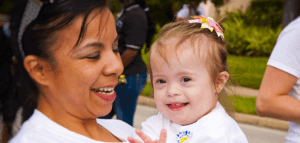 Parent holding smiling child with special needs