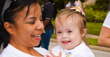 Parent holding smiling child with special needs