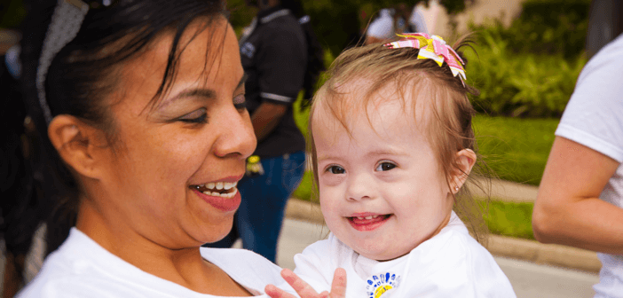 Parent holding smiling child with special needs