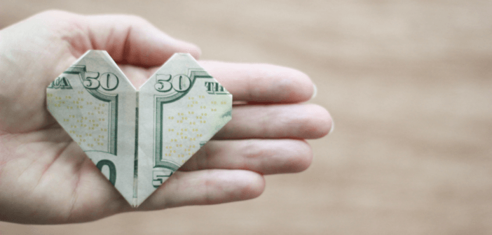 $50 bill folded into an origami heart in the open palm of a person's hand