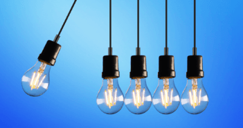 A lightbulb hanging on a cord crashing into four other lightbulbs on cords