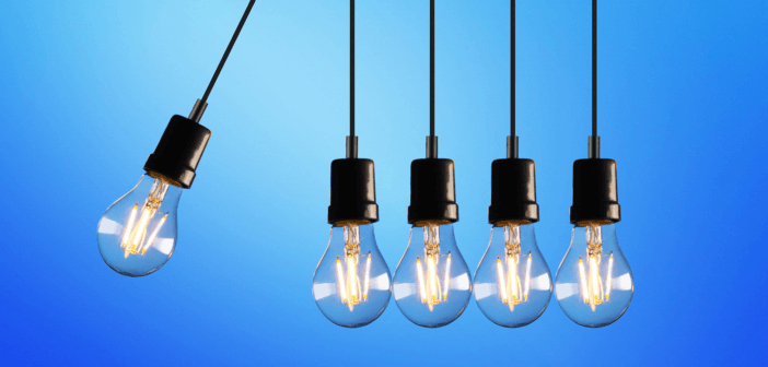 A lightbulb hanging on a cord crashing into four other lightbulbs on cords