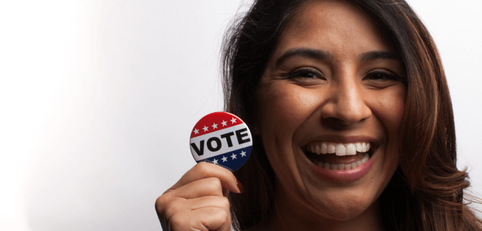 Smiling person holding a VOTE button