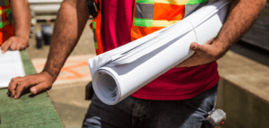 Construction person holding rolled-up drafting papers