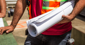 Construction person holding rolled-up drafting papers