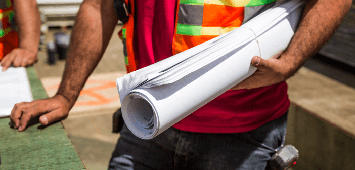 Construction person holding rolled-up drafting papers