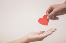 Giving for the Right Reasons A person's hand placing a paper heart in the outstretched hand of another person