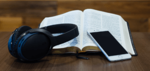 Headphones, a cell phone, and an open Bible