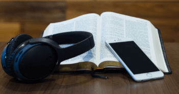 Headphones, a cell phone, and an open Bible