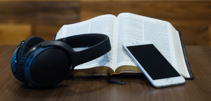 Headphones, a cell phone, and an open Bible