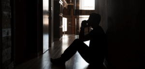 Person sitting on the floor in a dark room praying