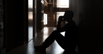 Person sitting on the floor in a dark room praying