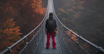 Person walking across a very long and very high pedestrian swinging bridge